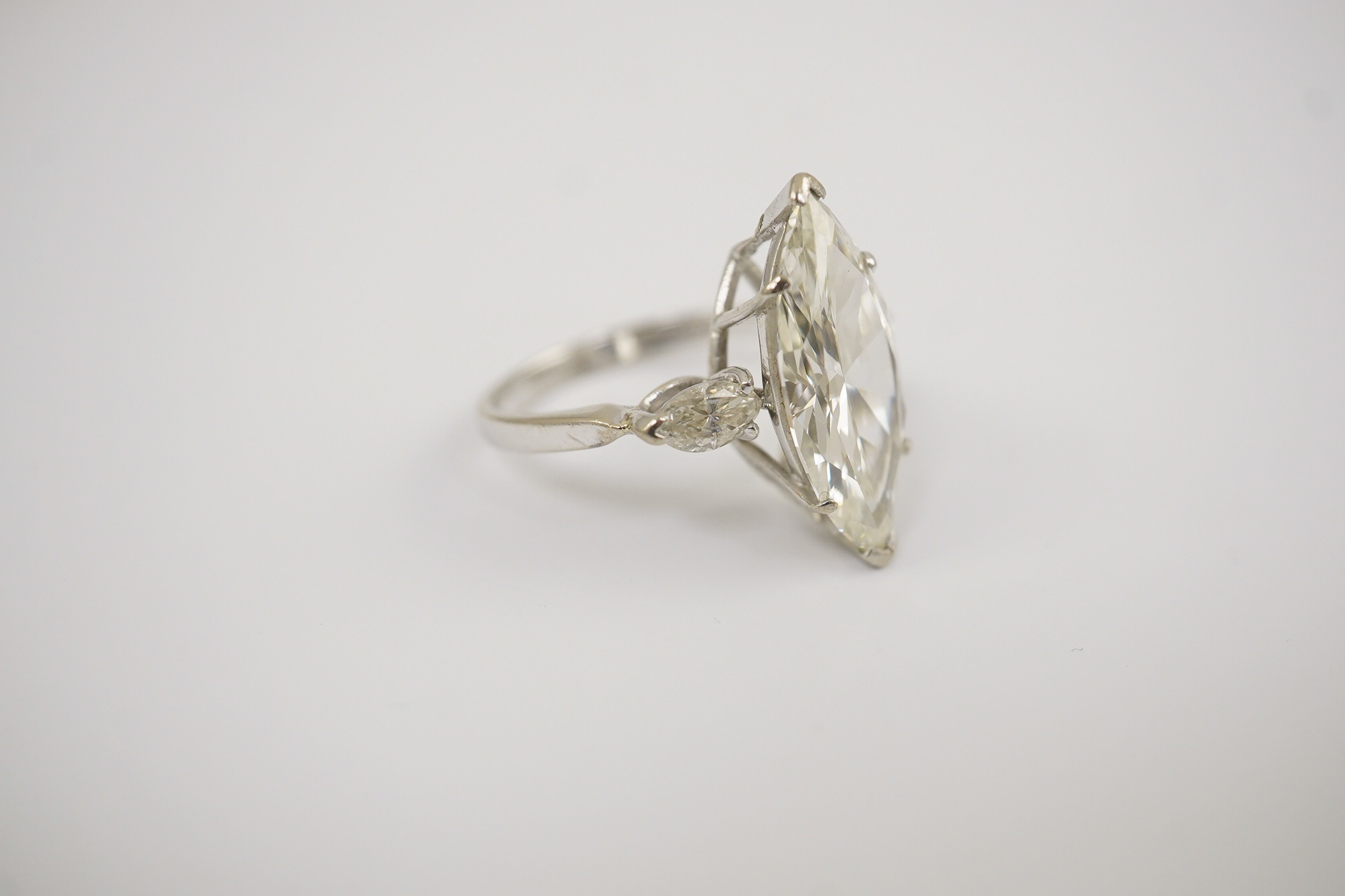 A modern 18ct white gold and single stone marquise cut diamond set ring, with two stone marquise cut diamond set shoulders